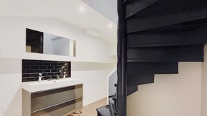 A modern bathroom with a white sink, black tiled backsplash, and a black staircase. - Luxurious Apartment - 3br/6p - Nation (Paris)