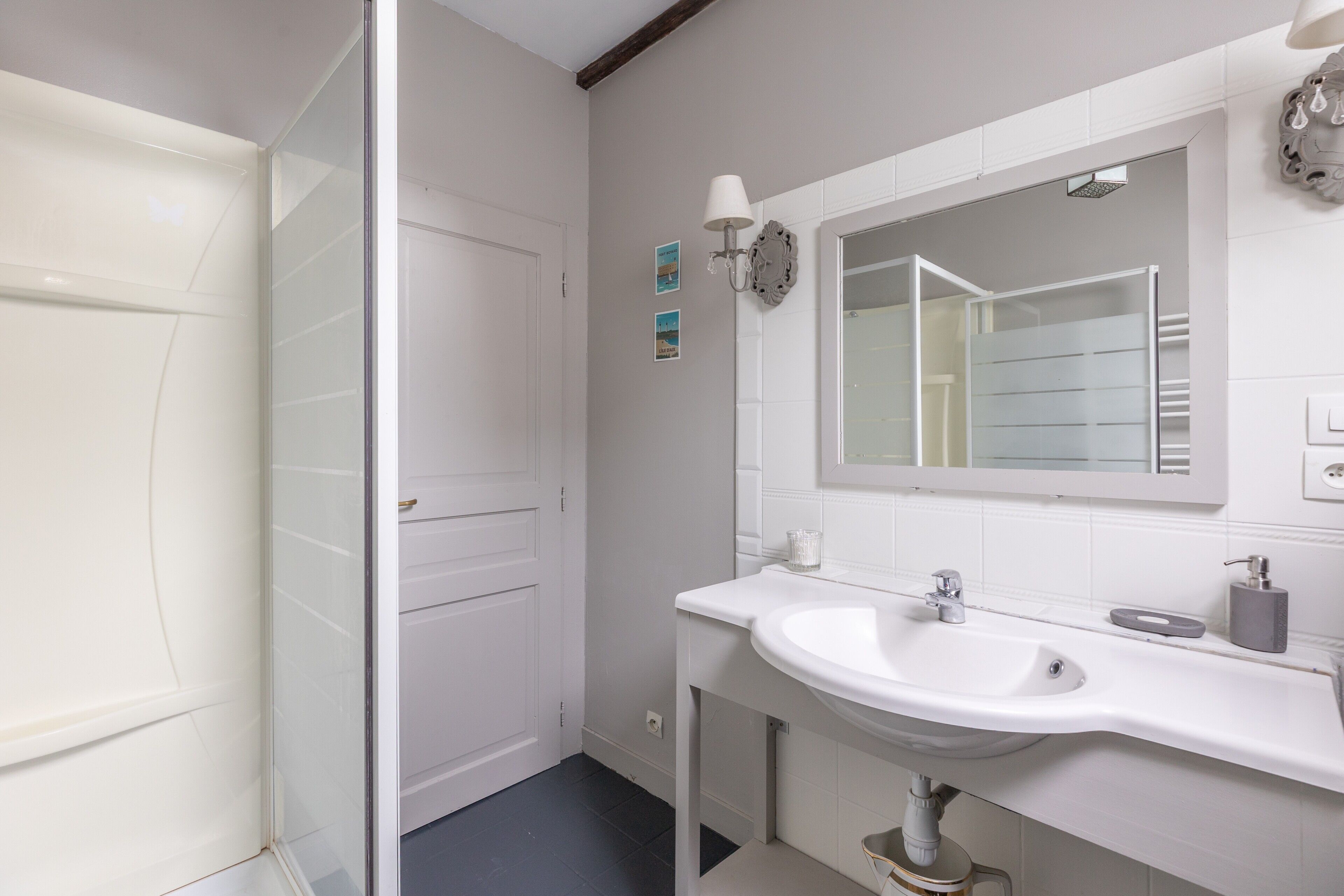 A bathroom with a white sink, mirror, and shower.
