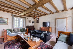 Un salon avec un plafond en bois, un canapé, une télévision et un piano.