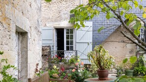 A rustic stone building with a wooden bench, a small table, and potted plants. - Guest Room 'Spacious Room in a Quiet Area' with Shared Garden and Wi-Fi (Cléré les Pins)