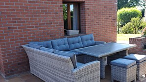 A wicker sectional sofa with cushions, a small table, and two ottomans on a patio with hexagonal tiles. - Laurette - Family home, Somme Valley (Sailly-Laurette)