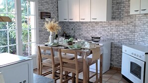 A kitchen with a brick wall, white cabinets, a dining table with chairs, and a white stove. - Laurette - Family home, Somme Valley (Sailly-Laurette)