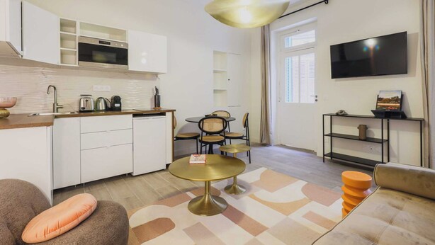 A modern kitchen with white cabinets, a built-in oven, and a dining area with a round table and chairs. - Cosy Apartment - 1br/2p- Saint-cloud (Saint-Cloud)