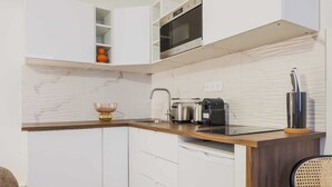 A modern kitchen with white cabinets, a wooden countertop, a built-in oven, and a coffee maker. - Cosy Apartment - 1br/2p- Saint-cloud (Saint-Cloud)