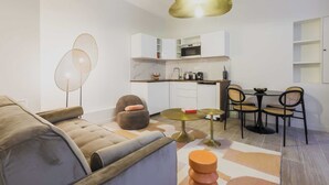 A modern living room with a sofa, a round table, and a dining area with chairs. - Cosy Apartment - 1br/2p- Saint-cloud (Saint-Cloud)