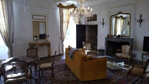A traditional living room with a fireplace, a chandelier, and classic furniture. - 15th century castle, up to 15 pax, pool and park (Artonne)