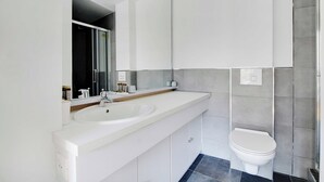 A modern bathroom with a white sink, mirror, and toilet. - Cozy Apartment 2bdr/5p - in the Heart of Suresnes (Suresnes)