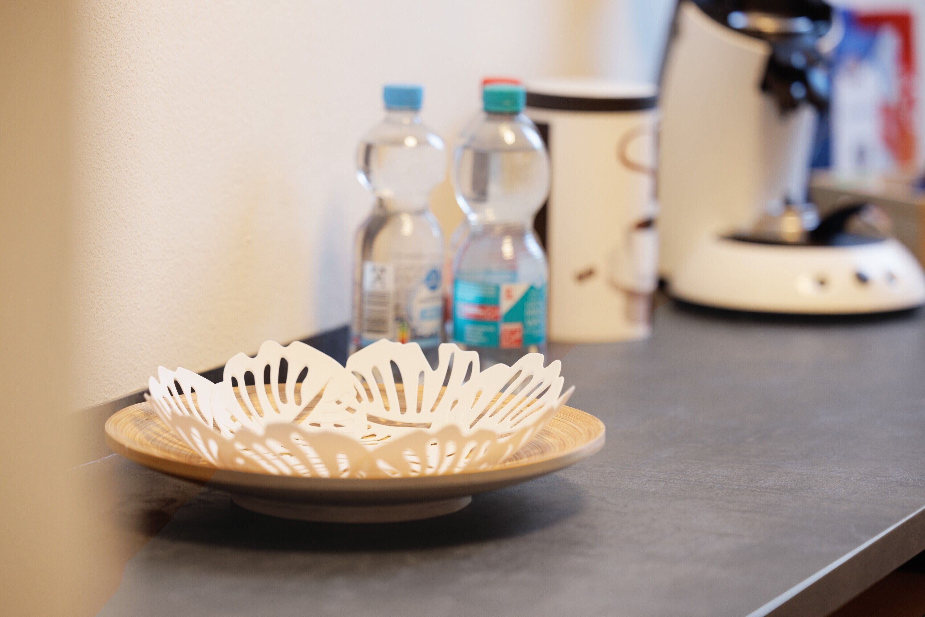 A kitchen counter with a decorative plate, two water bottles, and a coffee maker.