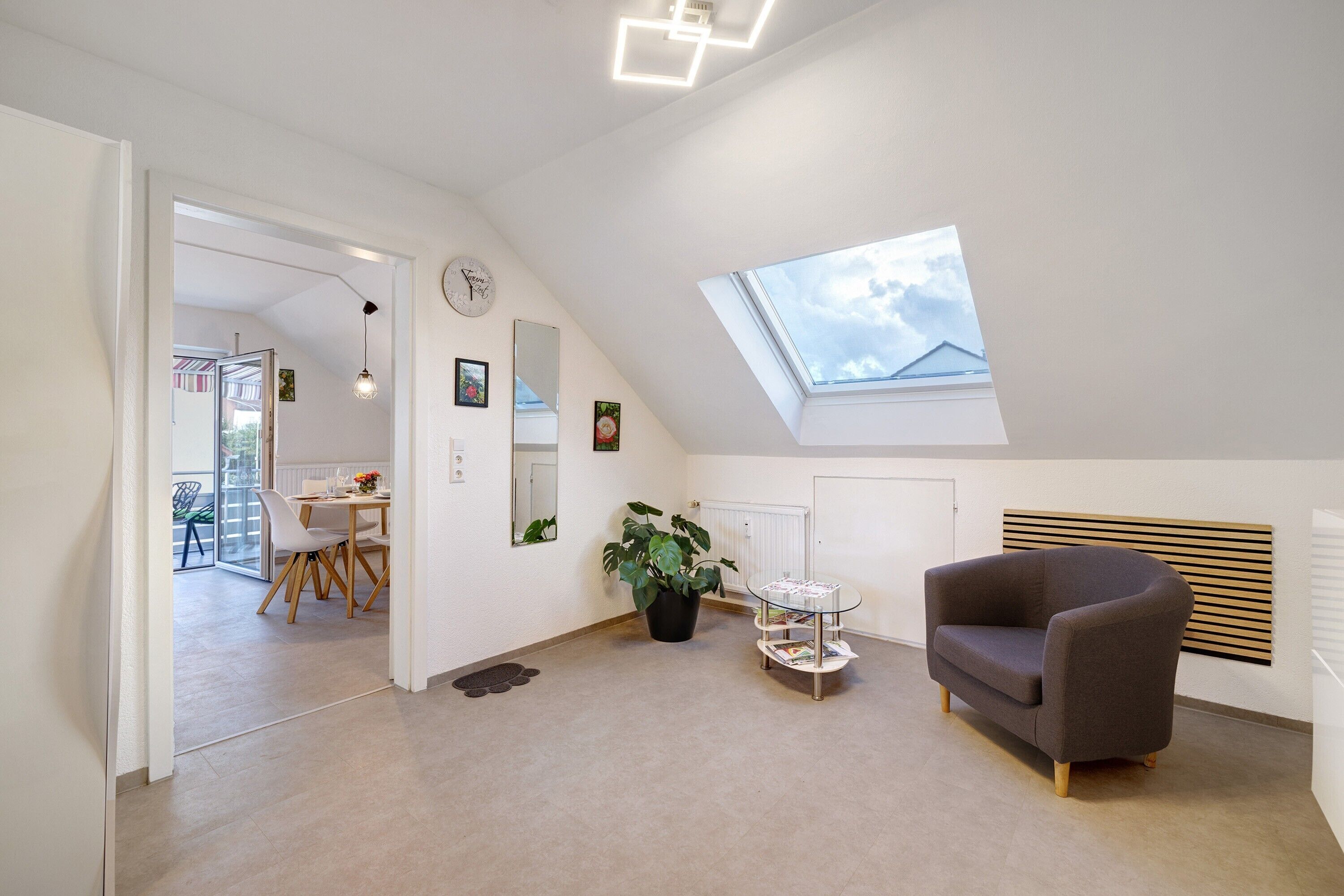 A modern living room with a skylight, a dining area, and a potted plant.
