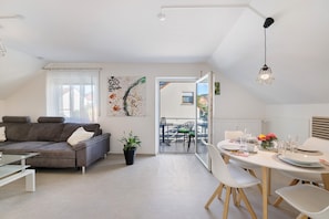 En moderne lejlighed med spiseplads, sofa og balkon.