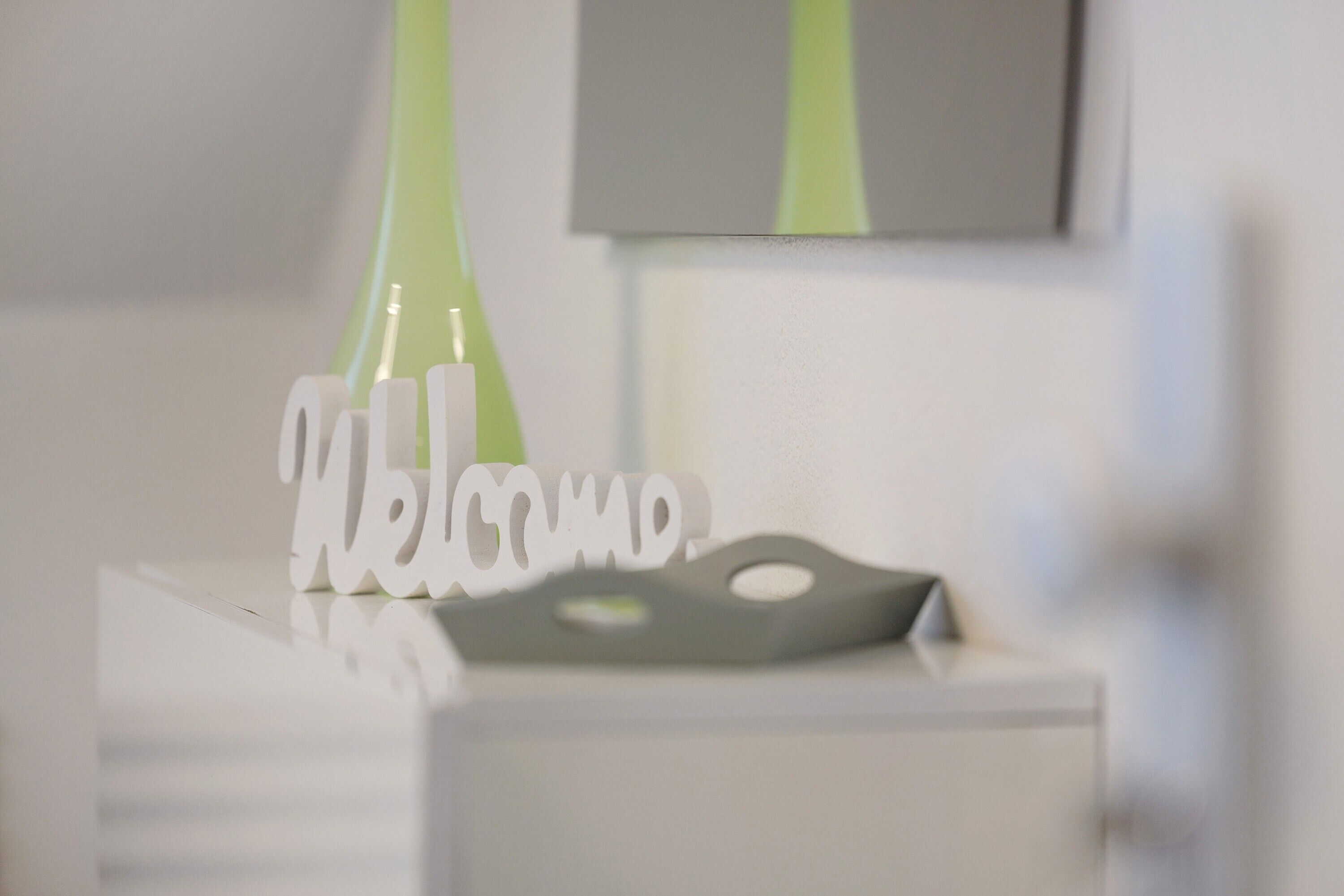 Un comptoir d’accueil avec une pancarte « Bienvenue » et un vase vert.