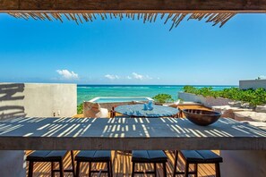 An outdoor seating area with a view of the ocean, a pool, and a thatched roof structure. - Antal by Beach Please Tulum (Tulum)