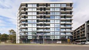 A multi-story building with balconies, large windows, and a sign advertising apartments for sale. - Bright 1BR Apartment with Stunning Views (Turner)