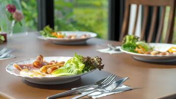 Une table à manger avec des assiettes remplies de nourriture, des couverts et une chaise.