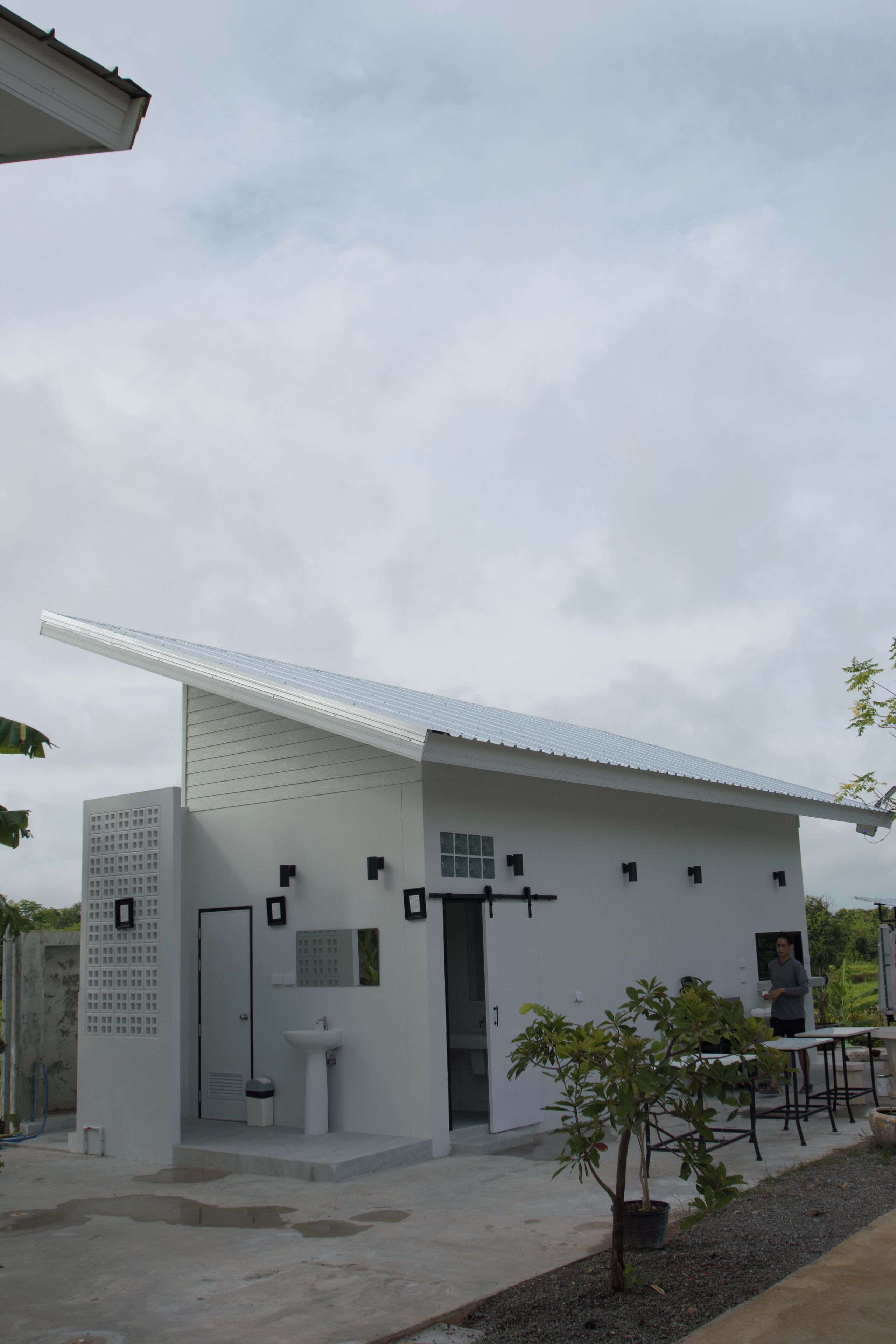 Um edifício moderno com telhado plano, uma pequena varanda e uma única porta.