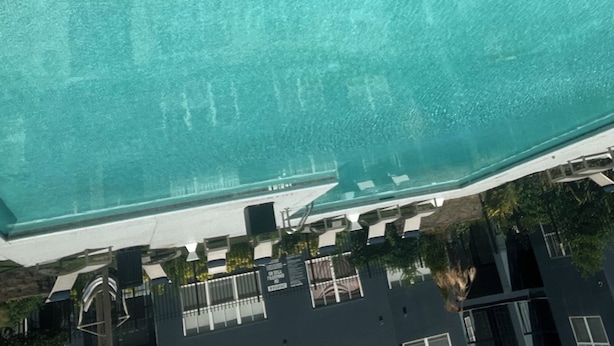 Une piscine dont le bord est revêtu de carrelage et qui est équipée d’une main courante en métal.