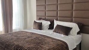 Une chambre à coucher avec un grand lit, une tête de lit et un ventilateur de plafond.