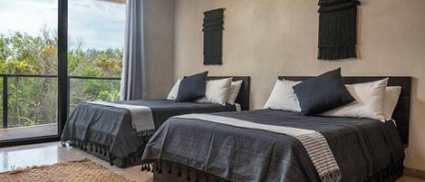 Une chambre moderne avec deux lits, de grandes fenêtres et une vue sur les arbres.