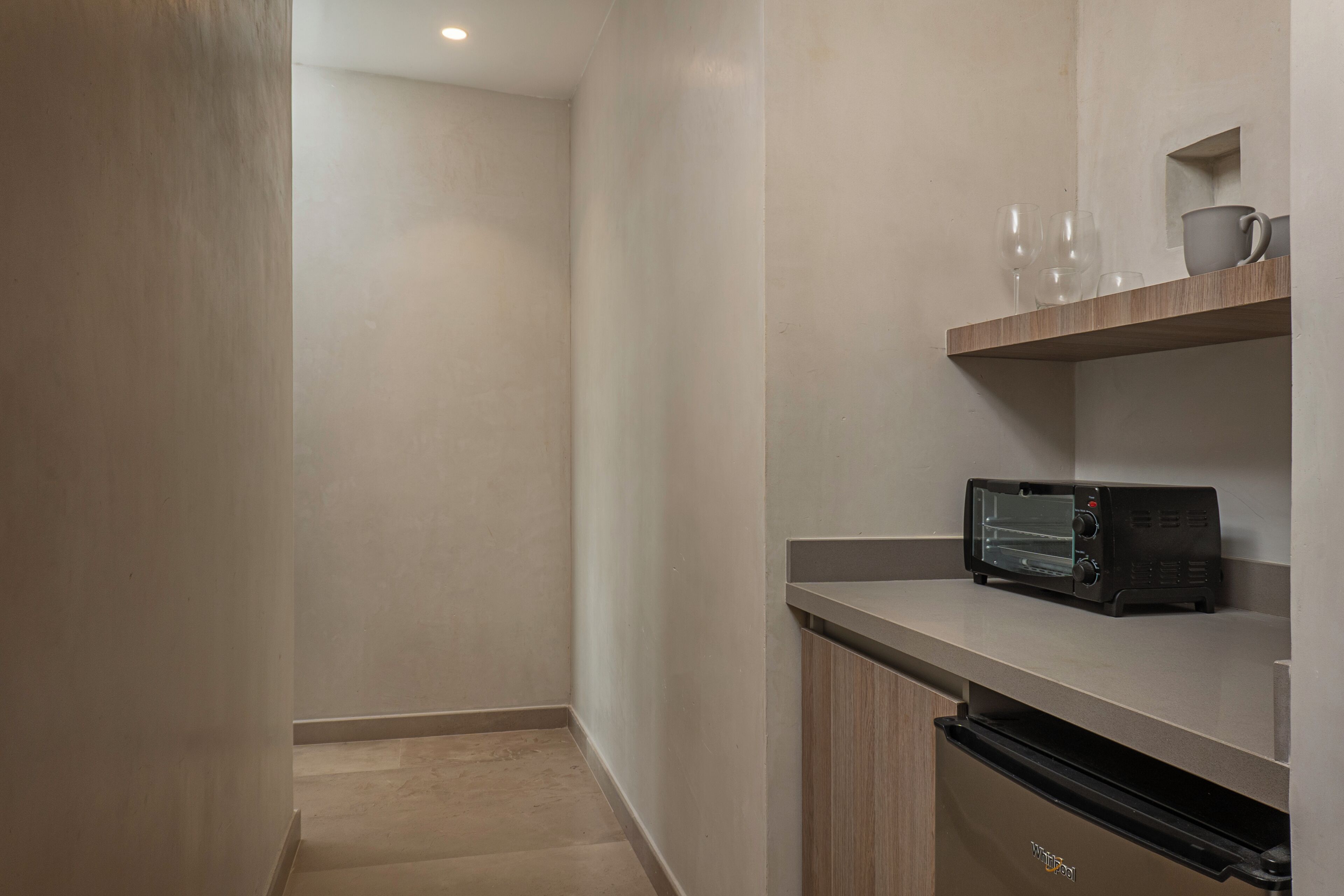 A kitchenette with a microwave, toaster, and a small shelf with cups and a mug.