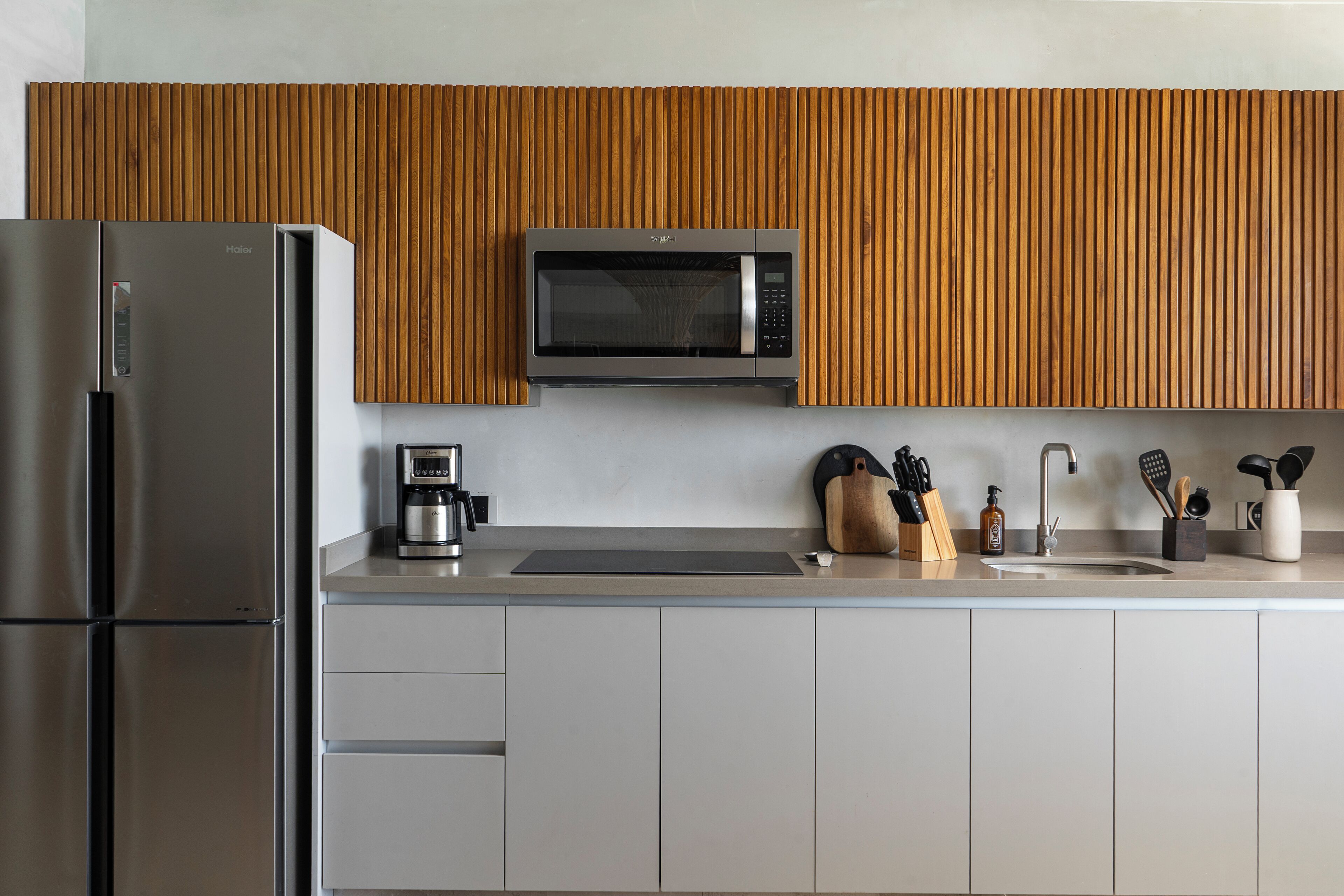 A modern kitchen with a stainless steel refrigerator, a microwave, and a coffee maker on the countertop.