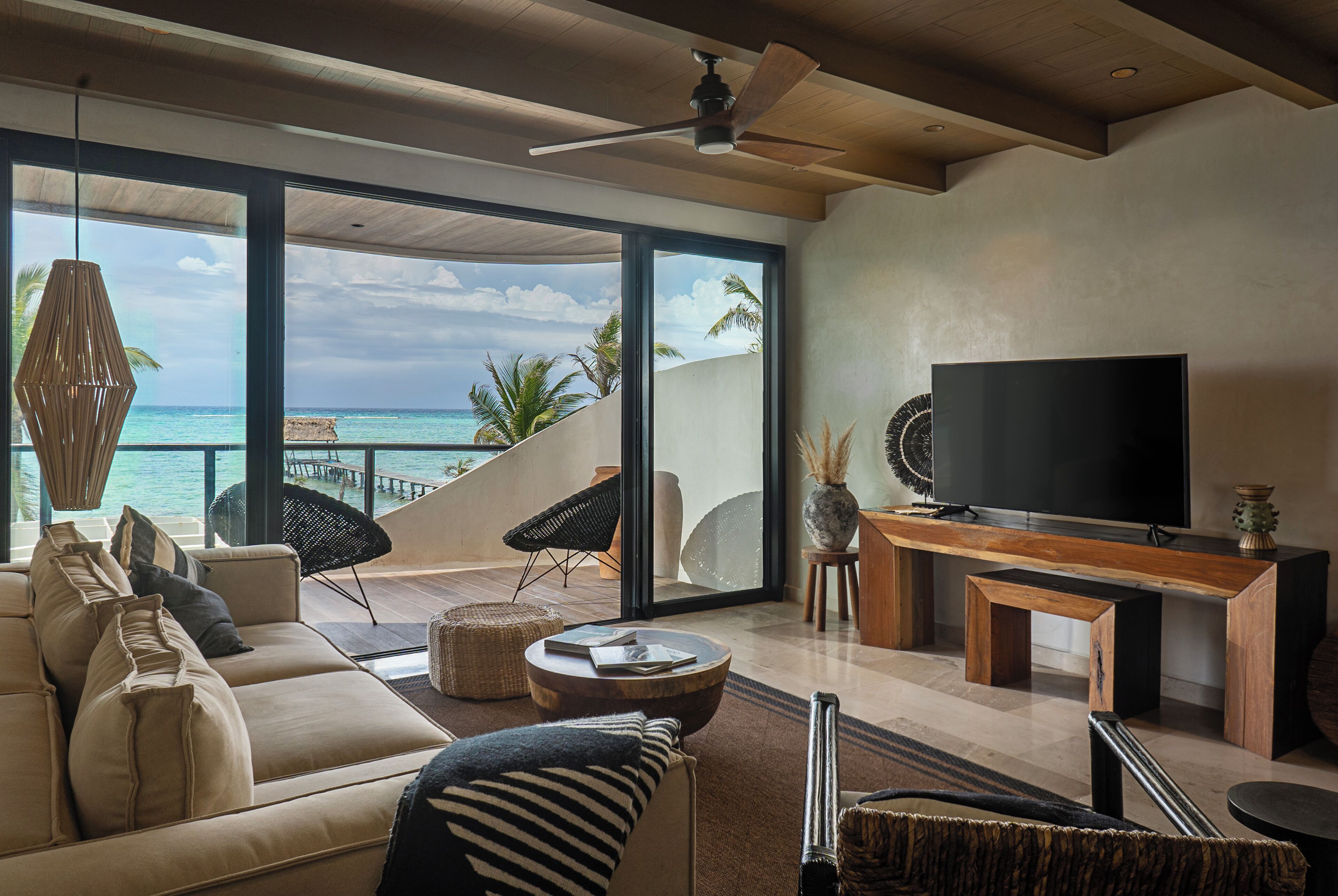 Een moderne woonkamer met een grote televisie, comfortabele zitplaatsen en uitzicht op de oceaan.