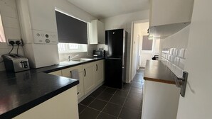 Una cucina moderna con mobili bianchi, un frigorifero nero, un tostapane e un forno a microonde.