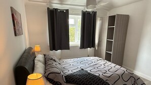 Una camera da letto con un letto, abat-jour, un armadio e una finestra con tende.