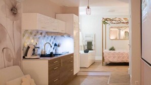 A modern living room with a sofa, a coffee table, and a kitchen area in the background. - La Parenthèse Fleurie – Suite with spa and projector screen in Bergerac (Bergerac)