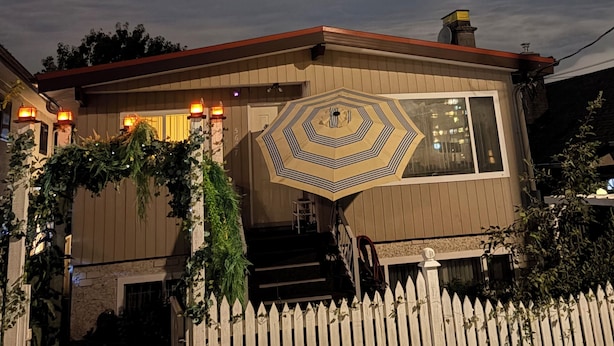 Une maison dotée d’une fenêtre hexagonale, d’une clôture en piquets et d’un escalier menant à l’entrée.
