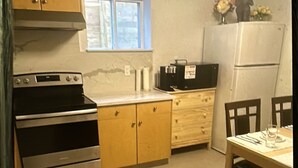 Une cuisine avec des meubles de rangement en bois, une cuisinière, un réfrigérateur et une table à manger.
