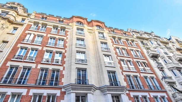 A multi-story building with a classic architectural style, featuring a central entrance with a large door and a balcony on the ground floor. - Charming Studio - 2P - Champs Elysees (Paris)