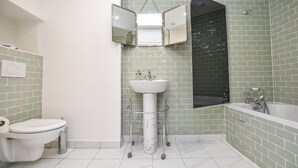 A bathroom with a white toilet, a pedestal sink, a mirror, and a bathtub. - Elegant Apartment - 3br/8p - Gare de L'est (Paris)