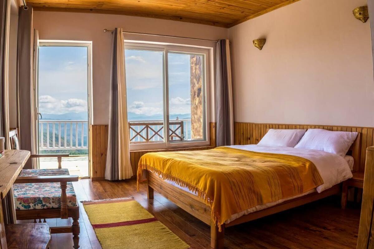 Une chambre avec un lit en bois, un balcon doté d’une balustrade et une vue sur le ciel.