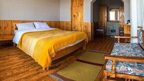 Una habitación de madera con una cama, un banco y una pequeña mesa.