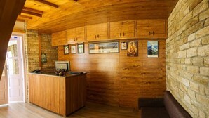 Un interior de madera con mostrador de recepción, cuadros enmarcados en la pared y una pared de piedra.