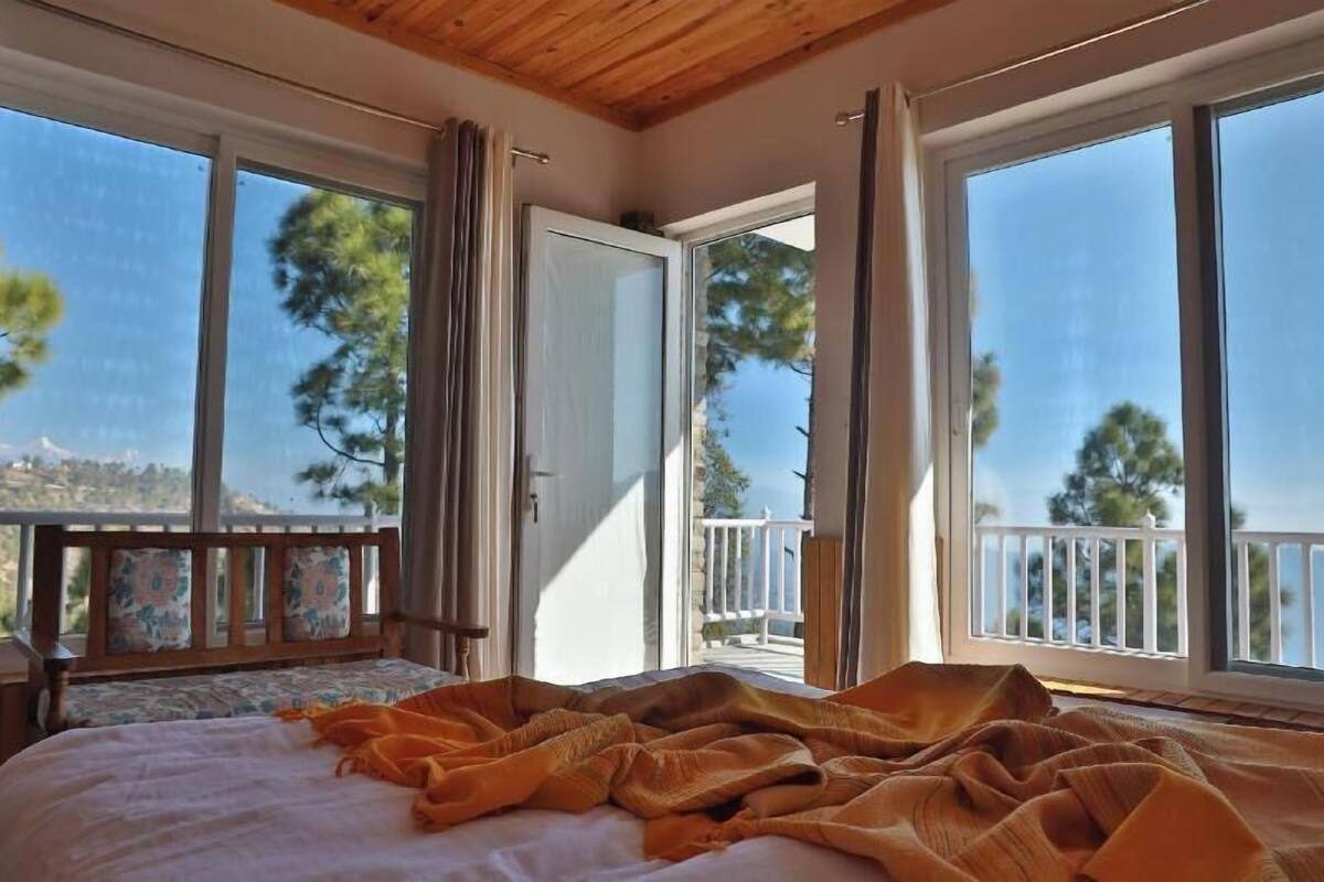 Une chambre à coucher avec un lit, un balcon et de grandes fenêtres.