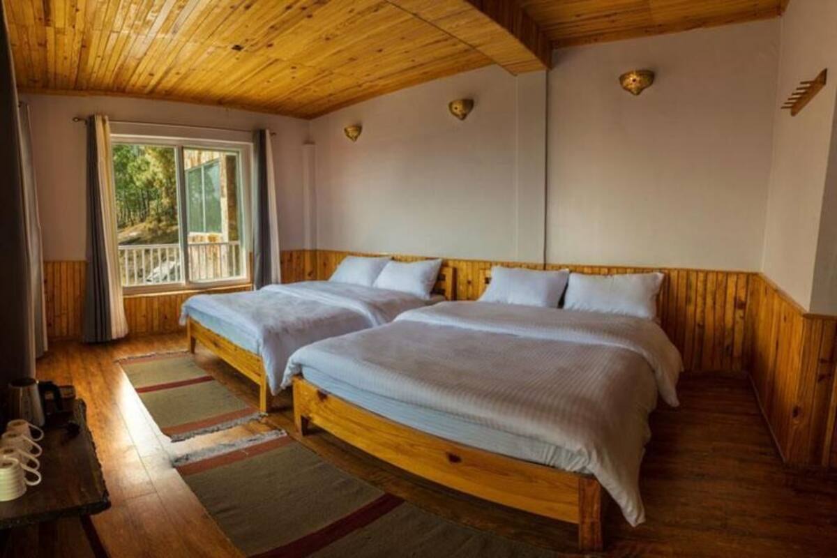 Une pièce avec deux lits en bois, une fenêtre avec des rideaux et un plafond en bois.