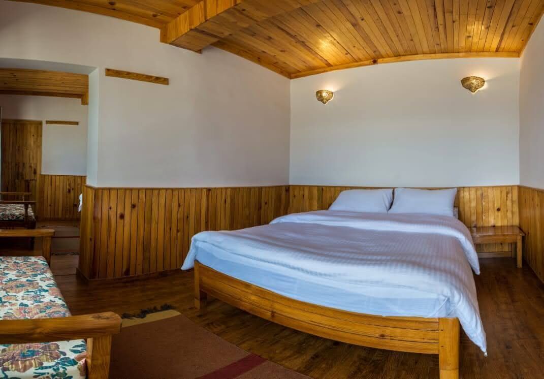 A wooden-paneled bedroom with a large bed, bedside tables, and a bench.