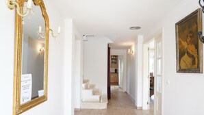 A hallway with a large mirror, a staircase, and a painting on the wall. - Spacious, good located villa in Sant Pere Pescador (Sant Pere Pescador)