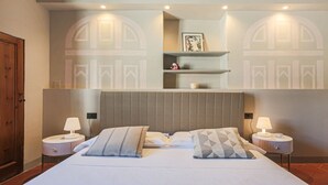 Une chambre d’hôtel avec un grand lit, deux tables de chevet avec des lampes, une tête de lit et un mur orné d’un motif géométrique.