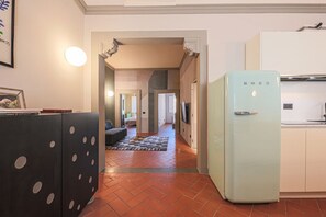 A kitchen with a light blue refrigerator, a black cabinet with circular patterns, and a tiled floor.