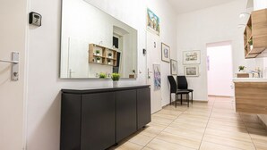 Un interior modern amb un mirall gran, un armari negre, una prestatgeria de fusta amb plantes i una cadira.