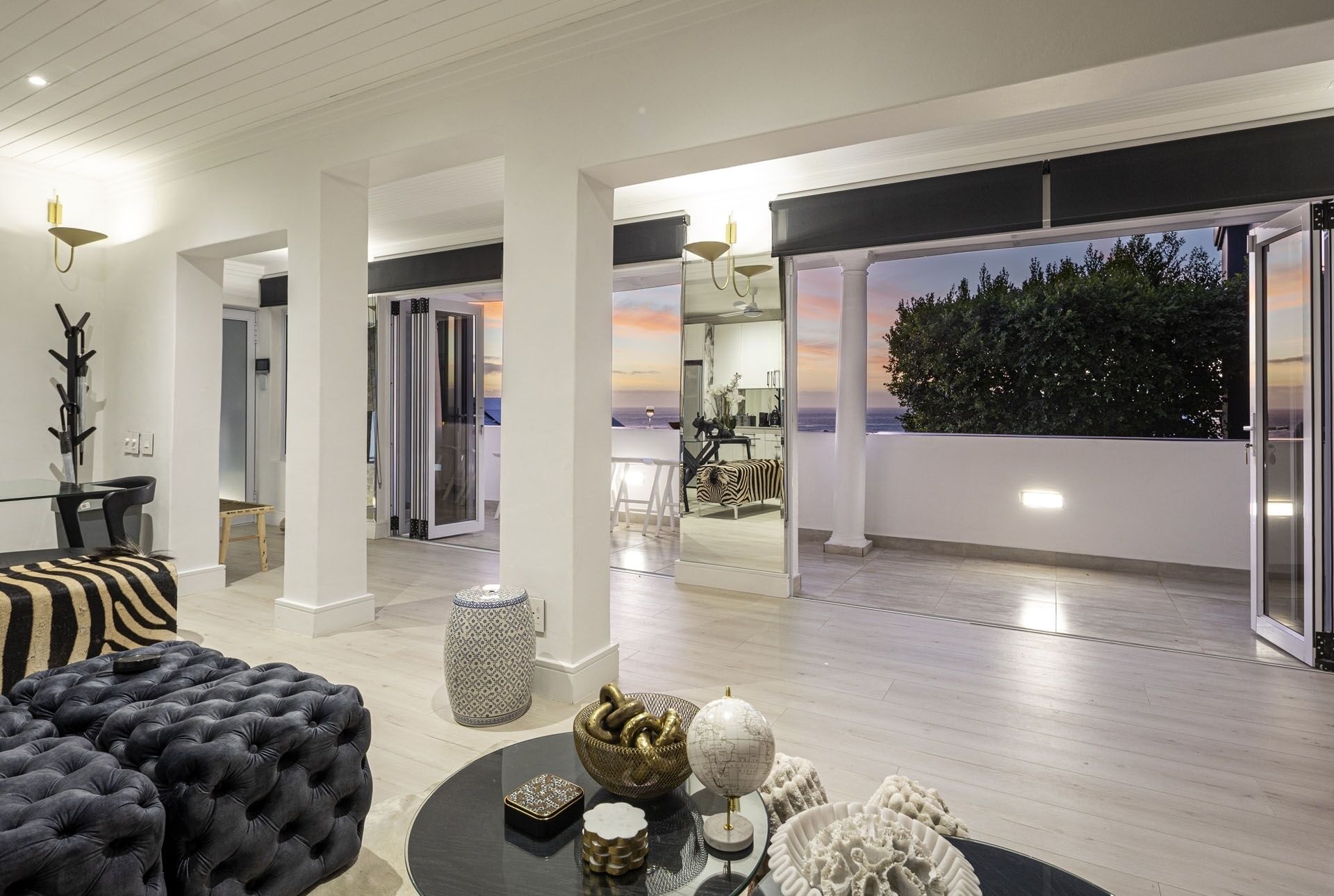 Un interior moderno con separador de vidrio, una zona de comedor y vista al mar.
