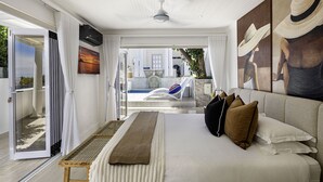 A modern hotel room with a large bed, a view of the pool, and a balcony. - YOLO Spaces - Clifton Petite Villa (Cape Town)