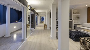 A modern interior with a long hallway leading to a living area, featuring a sofa, a coffee table, and a fireplace. - YOLO Spaces - Clifton Petite Villa (Cape Town)