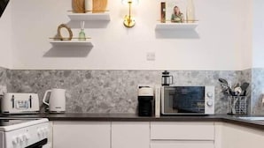 A modern kitchen with white cabinets, a microwave, a coffee maker, and a toaster. - Finnieston 1BR | Walk to Hydro & SEC | Parking (Glasgow)