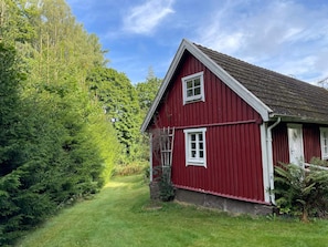 A red wooden house with a sloped roof, a visible window, and a door.