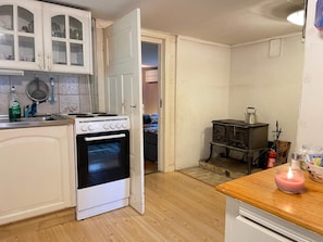 A compact kitchen with white cabinetry, a stove, and a small wooden table.