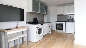 A modern kitchen with a built-in washing machine, a coffee machine, and a microwave. - SEA HOUSE Madeira (Funchal)