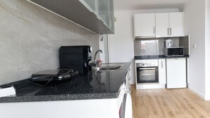A modern kitchen with a black countertop, stainless steel sink, and white cabinets. - SEA HOUSE Madeira (Funchal)